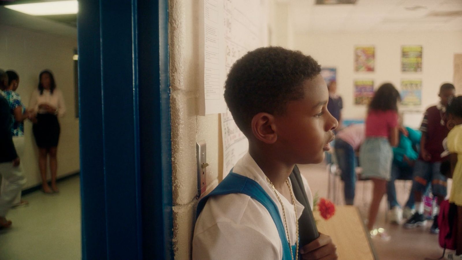 a young boy standing in a hallway next to a wall