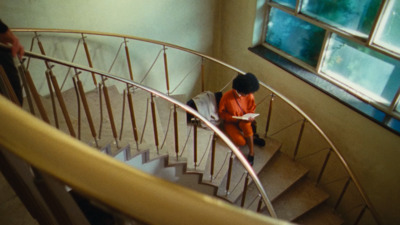 a woman in an orange coat is walking down a set of stairs