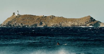 a person riding a surfboard in the ocean near a small island