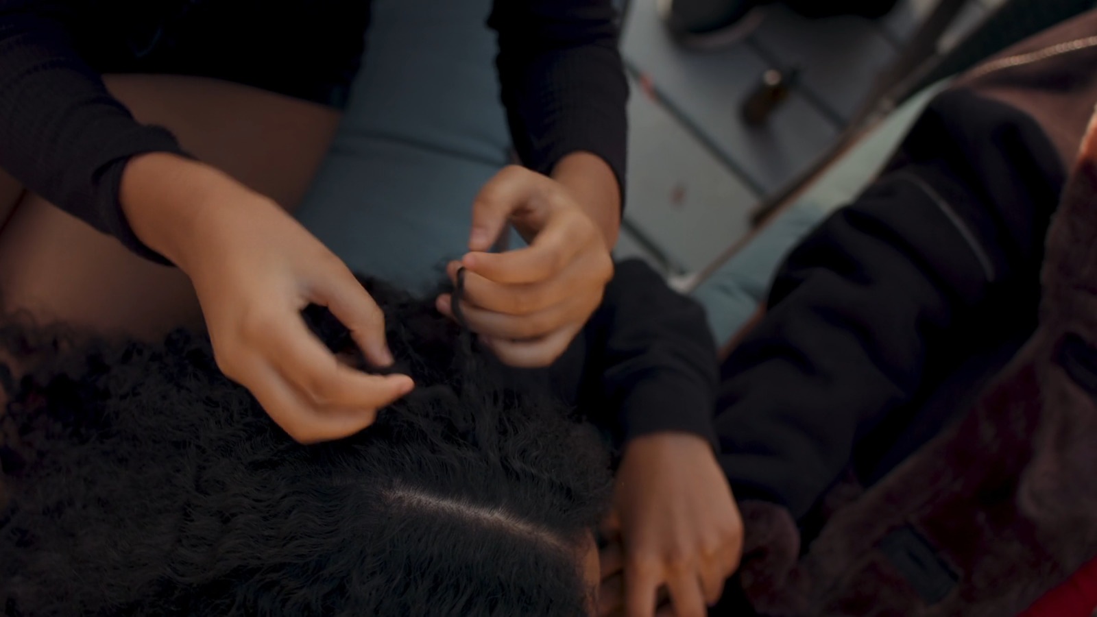 a person cutting another persons hair with scissors