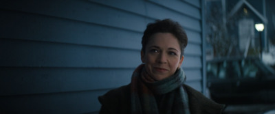 a woman standing outside of a house at night