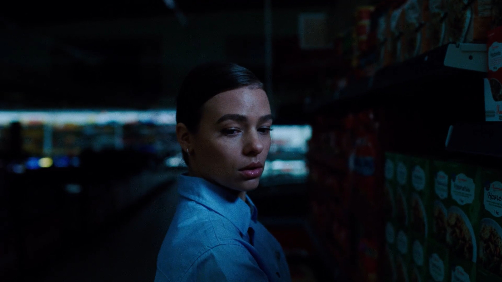 a woman in a blue shirt and tie in a dark room