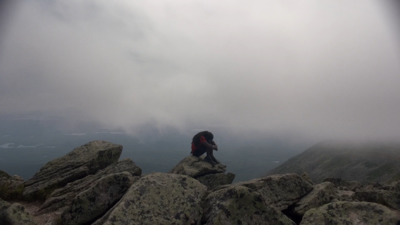 a person sitting on top of a large rock