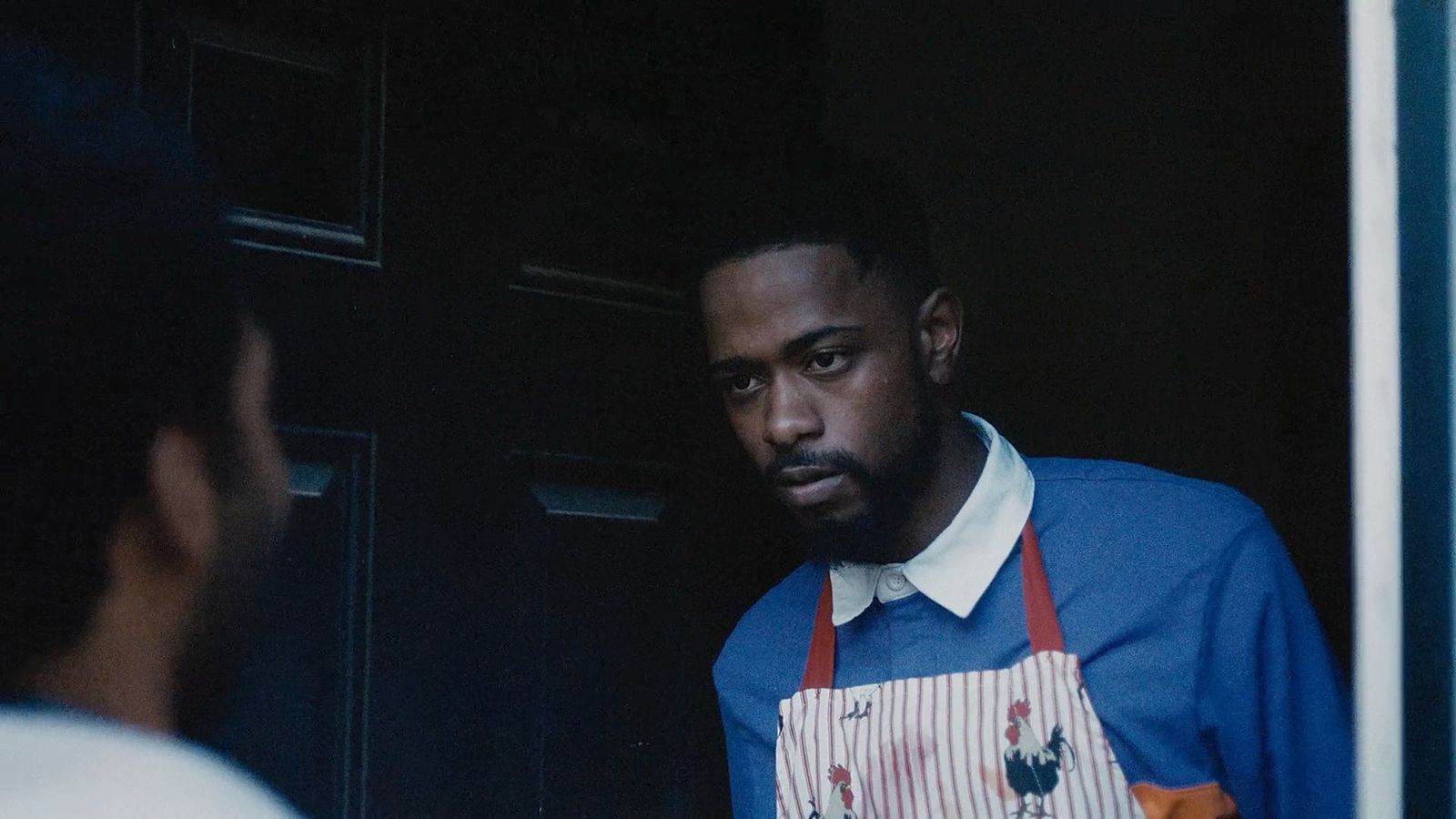 a man wearing an apron looking out a window