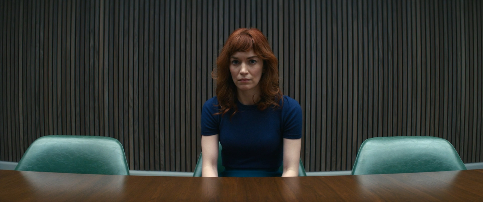 a woman sitting at a table in front of a wall