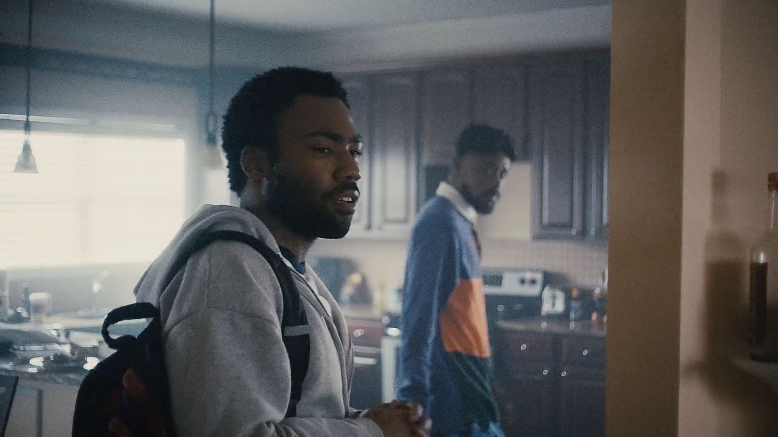 a man standing in a kitchen next to another man