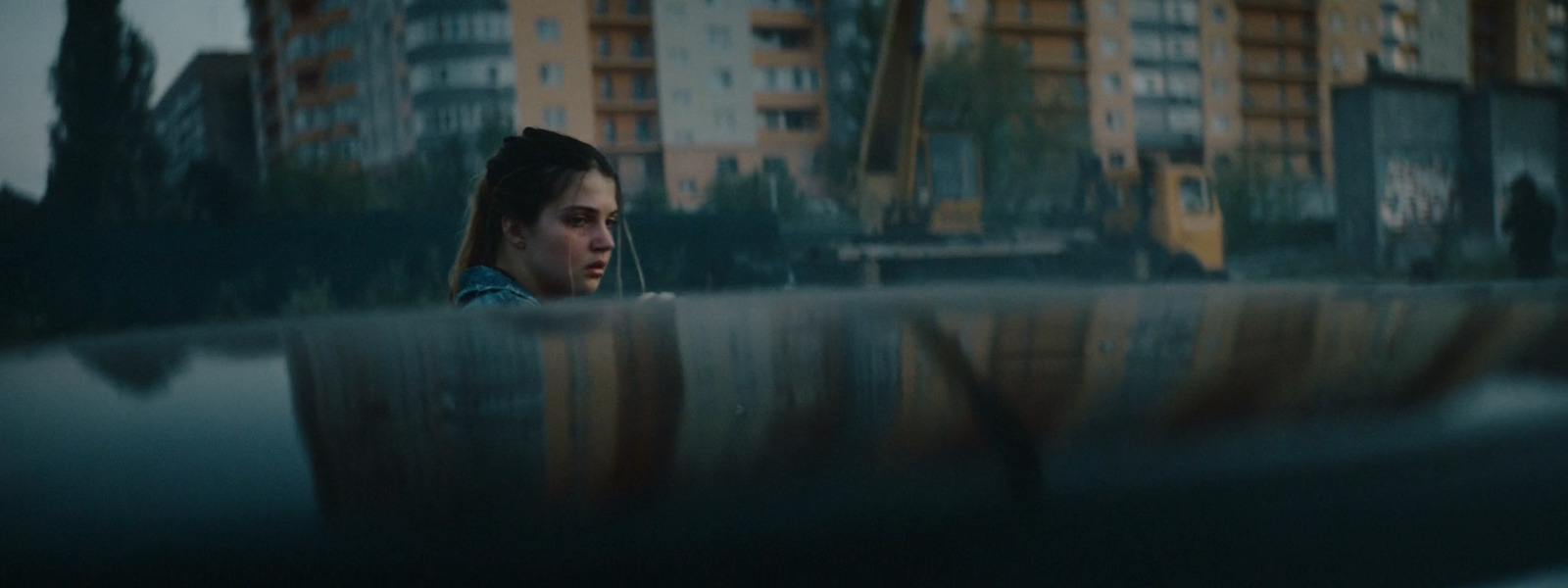 a woman sitting on a bench in front of tall buildings