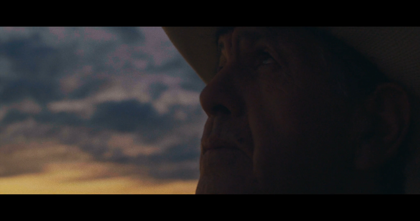 a man in a hat looking out at the sky