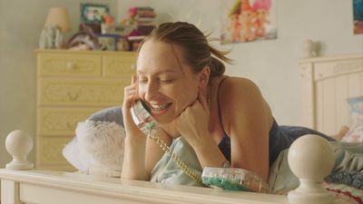 a woman laying on a bed talking on a cell phone