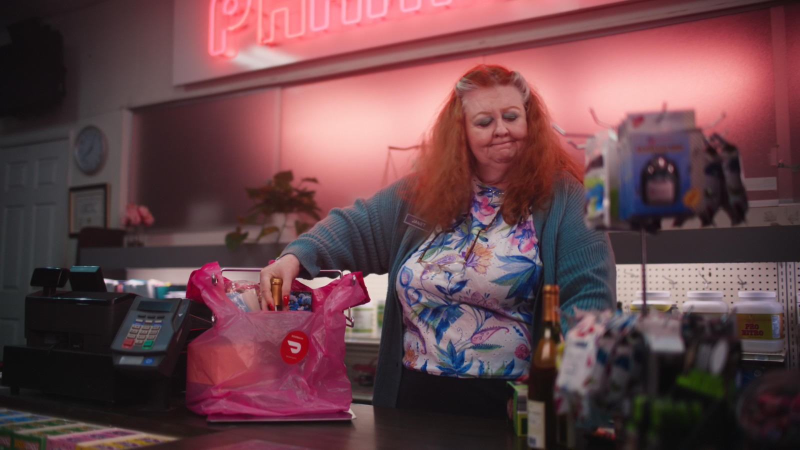 a woman standing at a counter with a pink bag