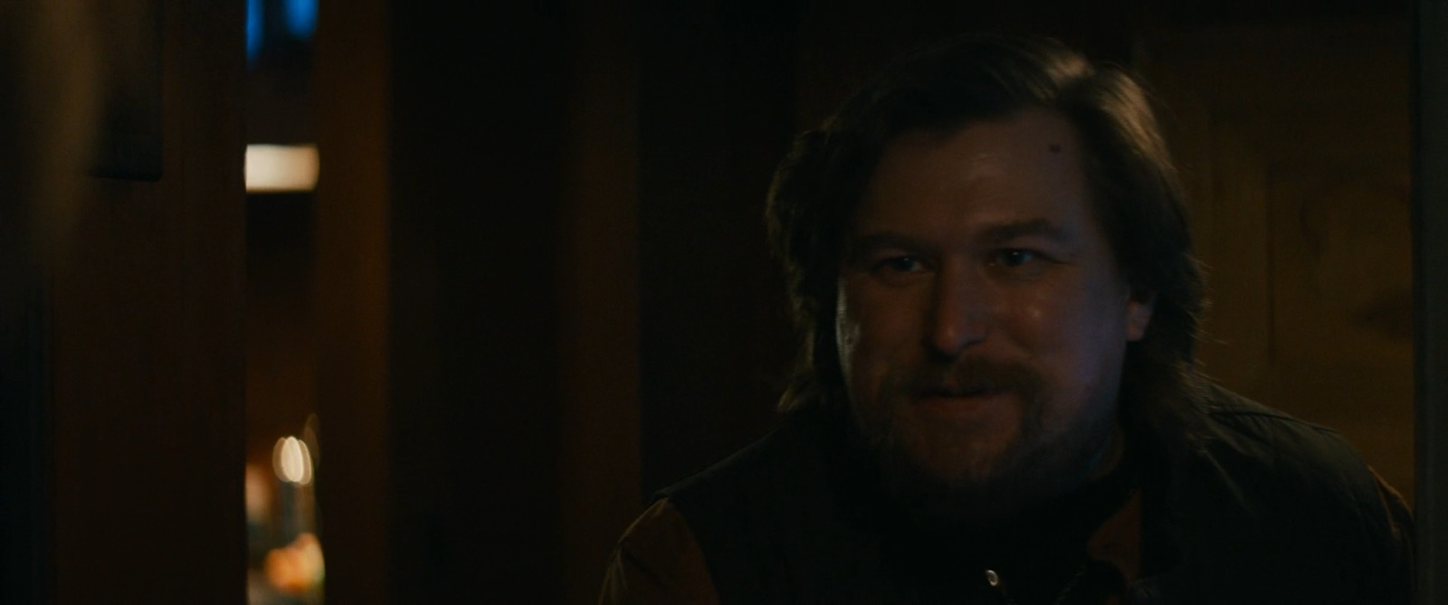 a man with long hair and a beard in a dark room