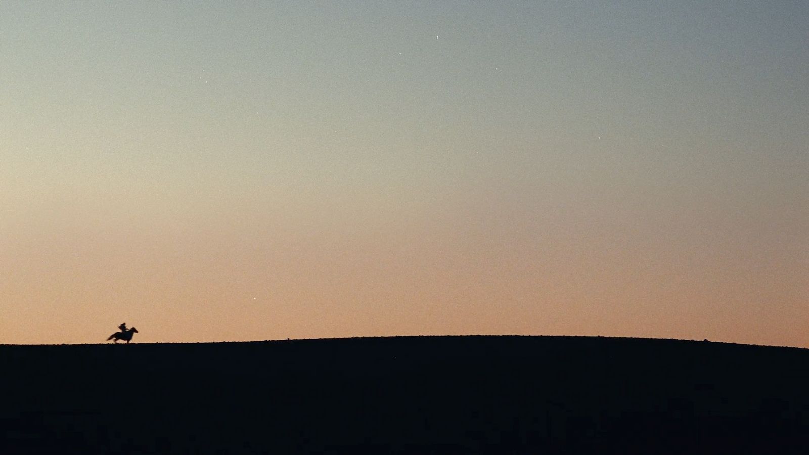 a person riding a horse on a hill at sunset