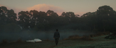 a person standing in a field next to a tent