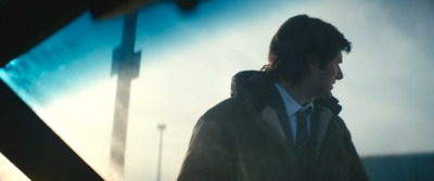 a man in a jacket and tie walking down a street