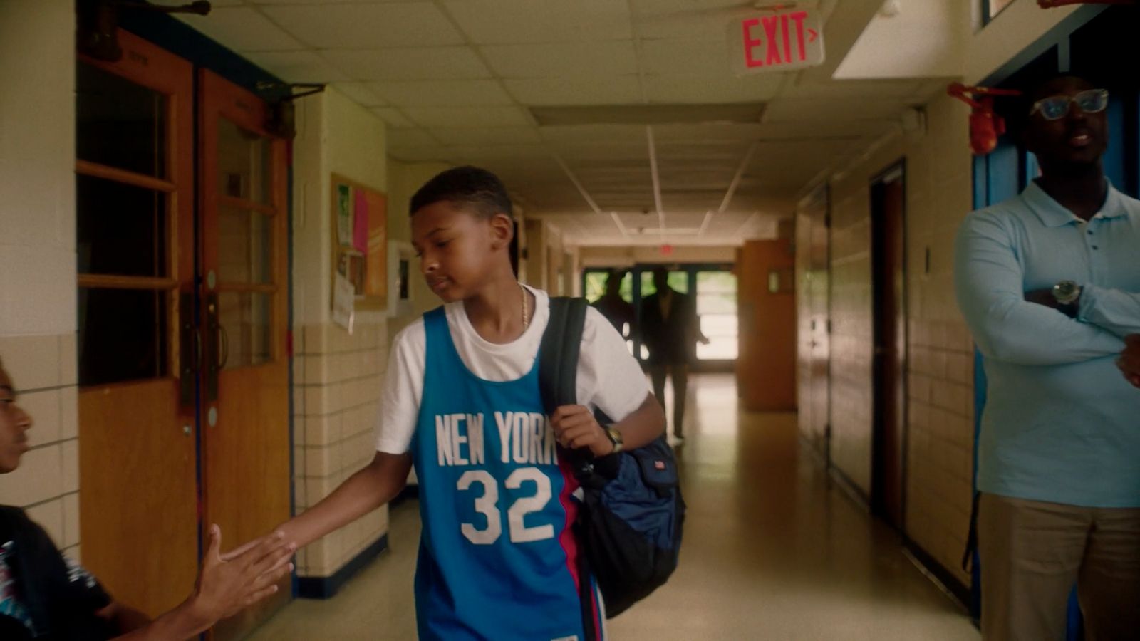 a woman in a blue jersey walking down a hallway