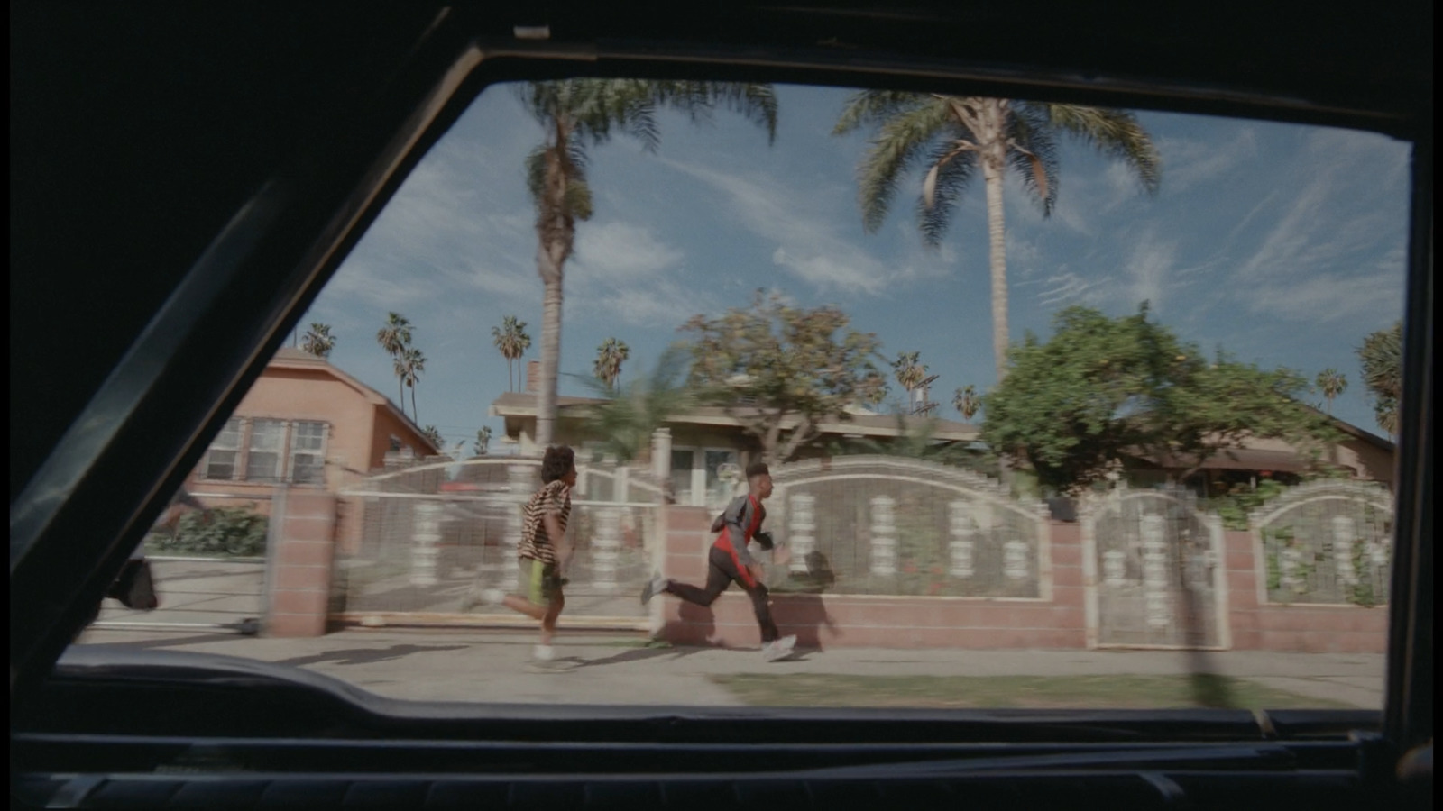 a man walking down a street next to a palm tree