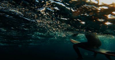 a man sitting on a surfboard under the water