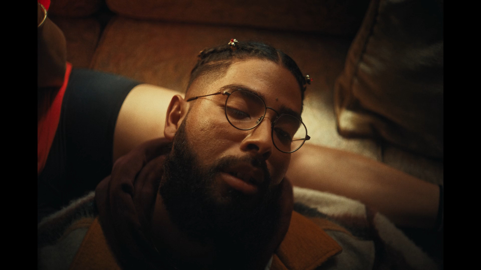 a man with glasses laying on a couch