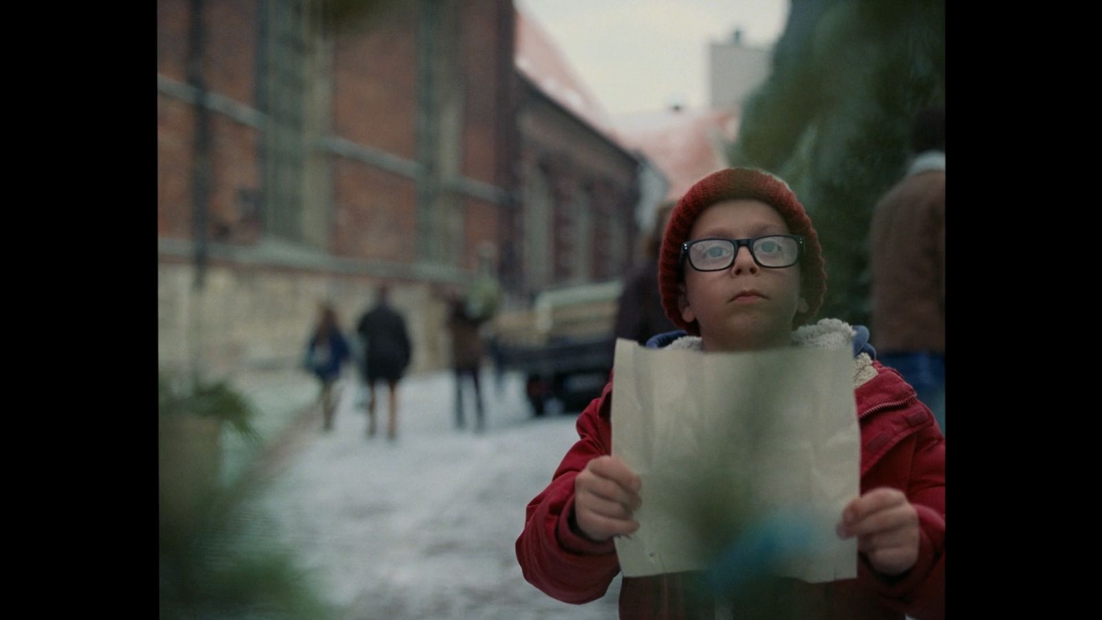 a young boy wearing glasses holding a piece of paper