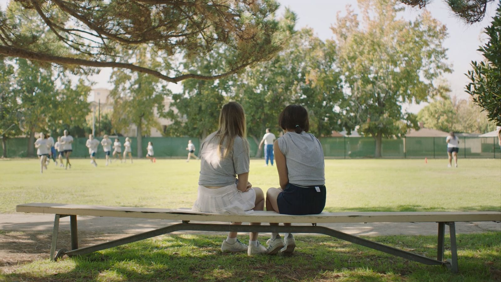 a couple of people sitting on top of a wooden bench