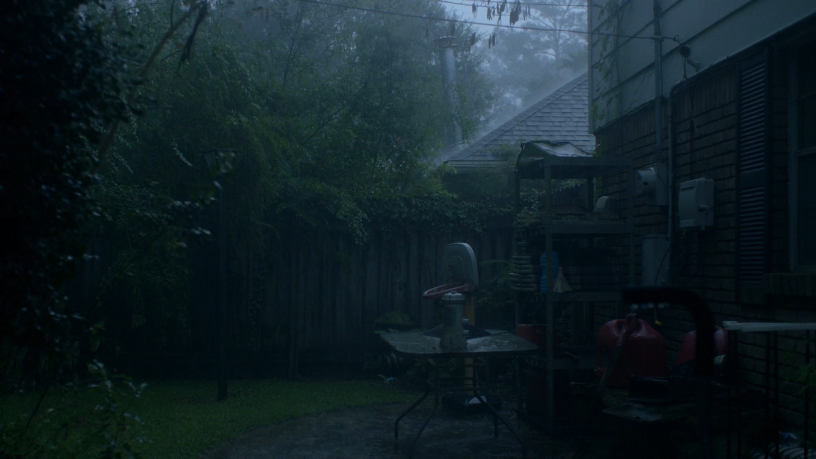 a back yard with a table and chairs in the rain