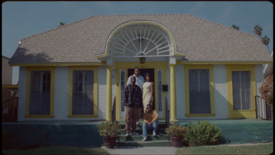 a man and a woman standing in front of a yellow house