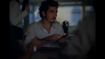 a man sitting at a table looking at a cell phone