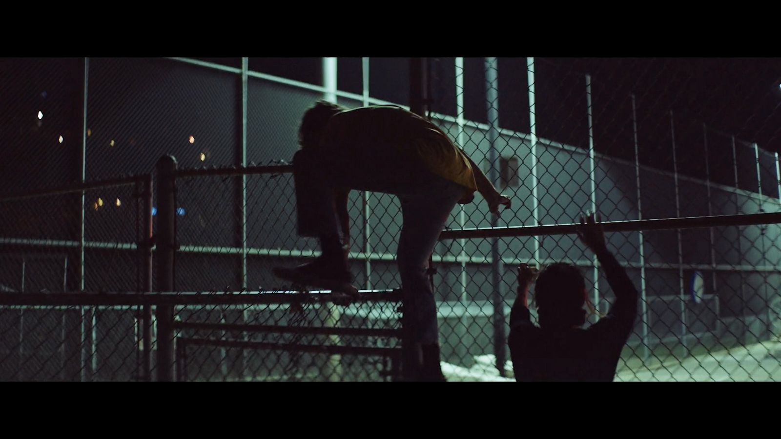 two people standing on a fence at night