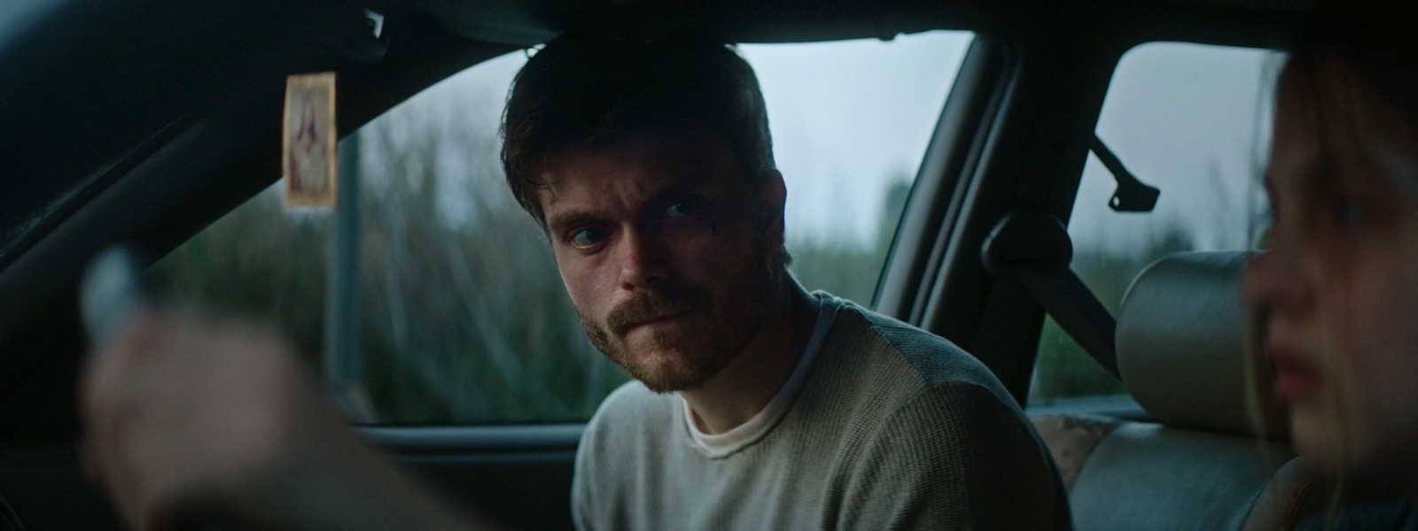 a man sitting in a car with a woman behind him