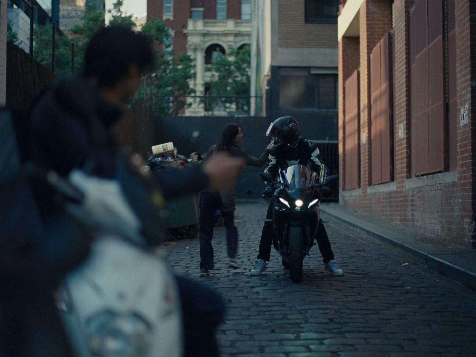 a man riding a motorcycle down a street next to a woman