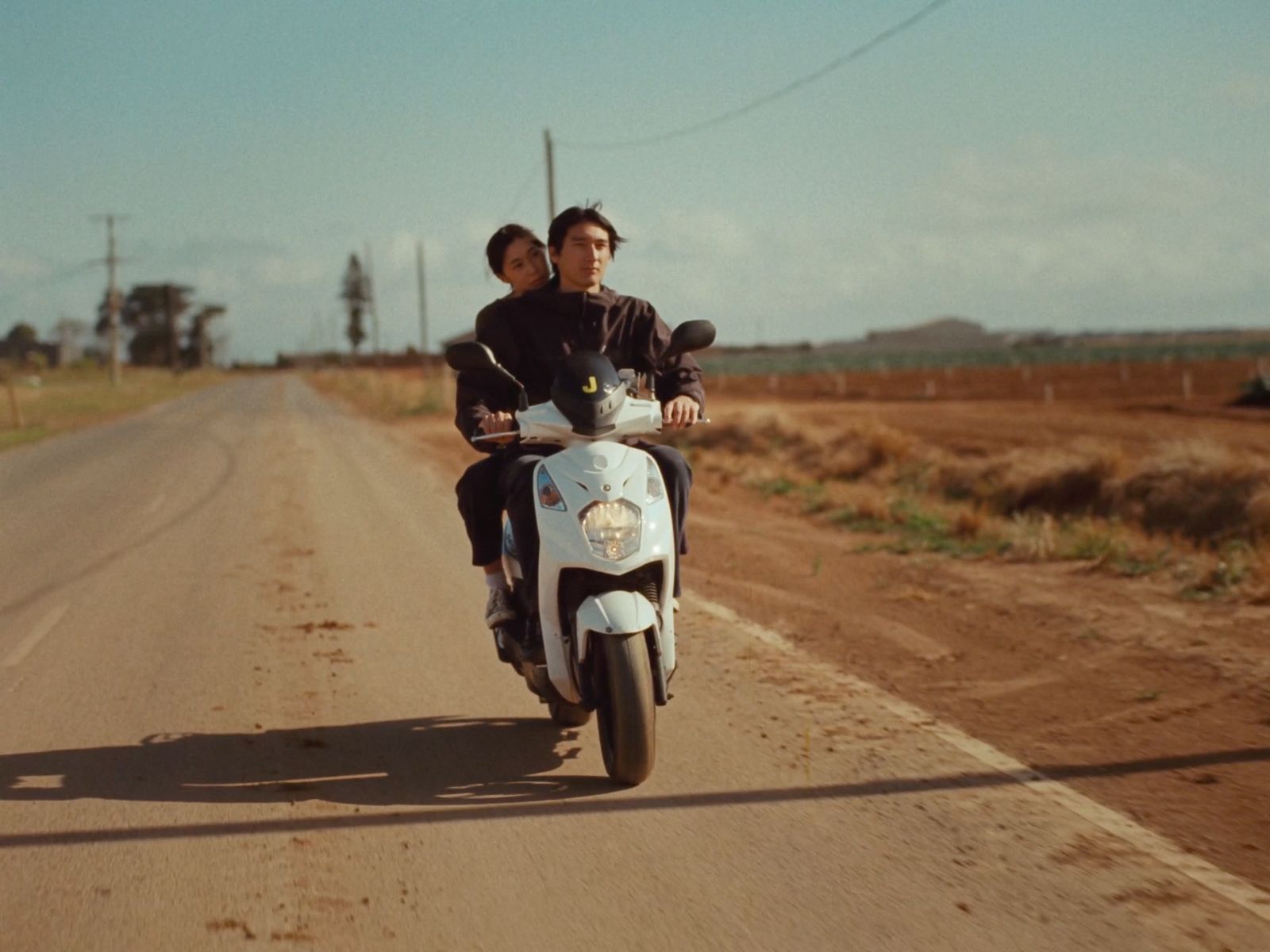 a man and a woman riding a motorcycle down a dirt road