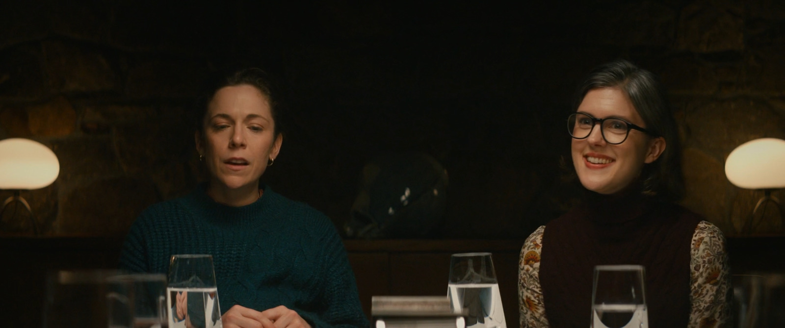 two women sitting at a table with wine glasses