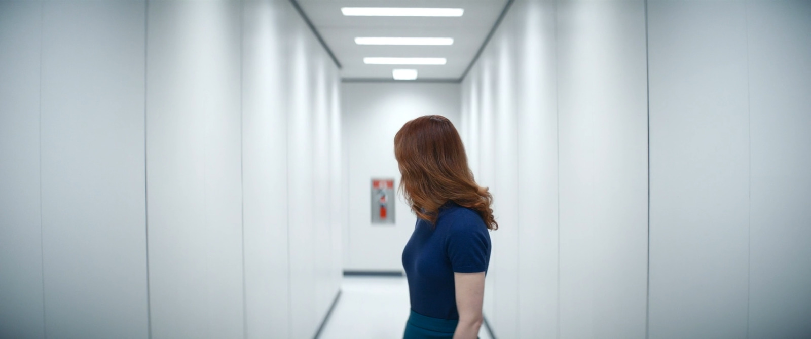 a woman in a blue dress walking down a hallway