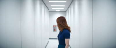 a woman in a blue dress walking down a hallway