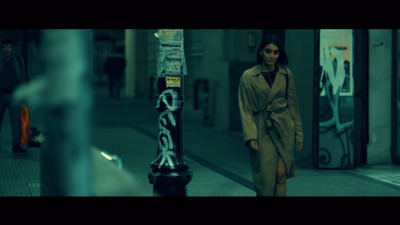 a woman in a trench coat walking down a street