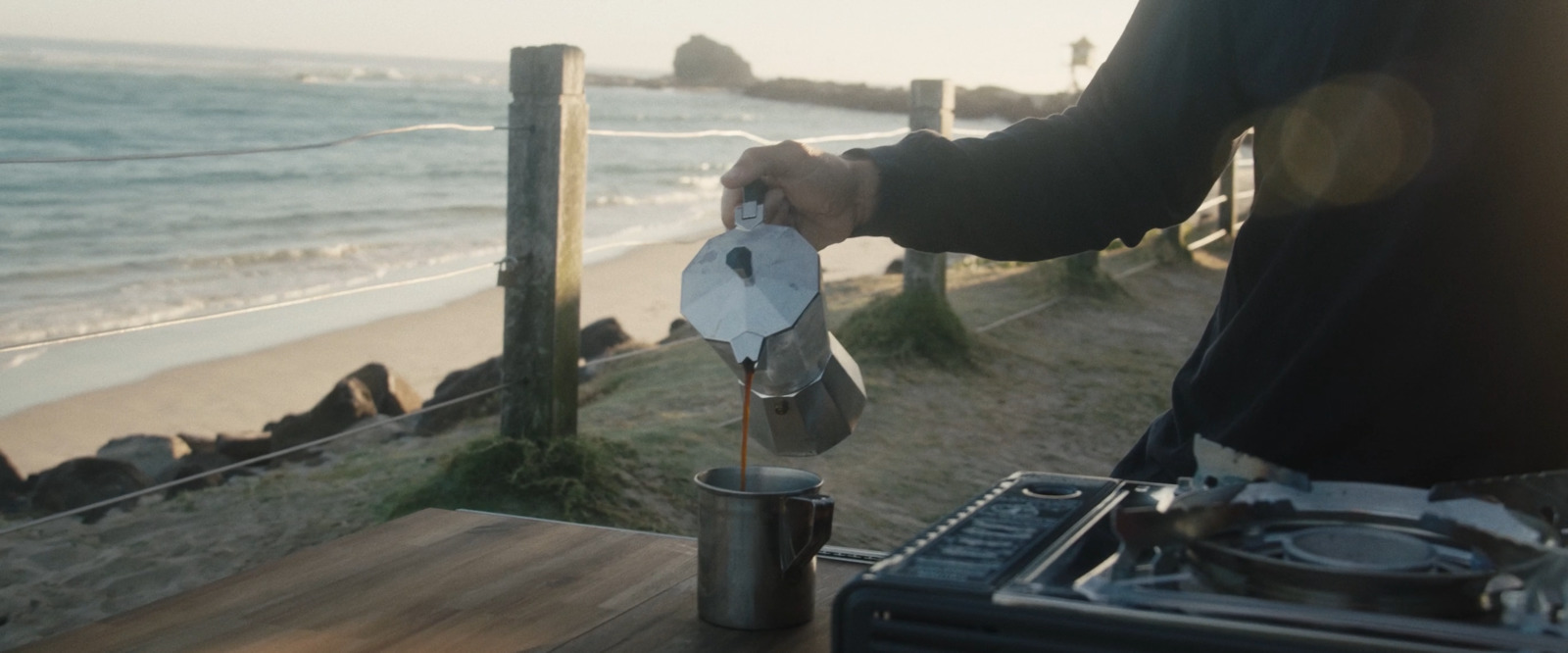 a person standing at a table near the ocean