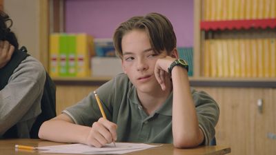 a boy sitting at a desk with a pencil in his hand