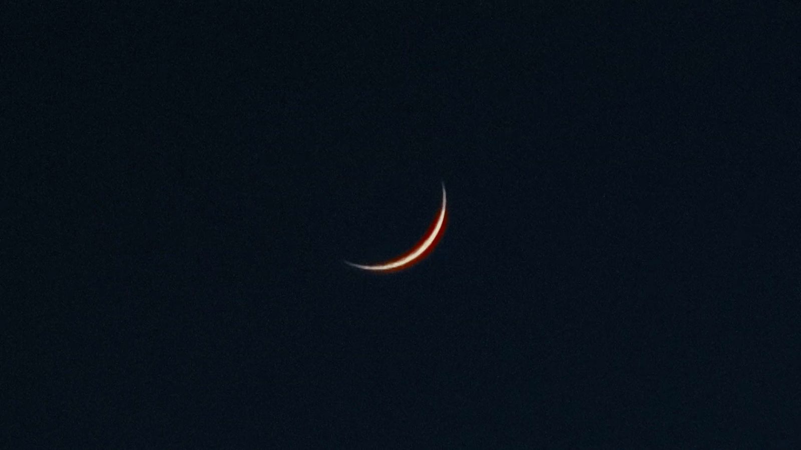 a crescent moon is seen in the dark sky