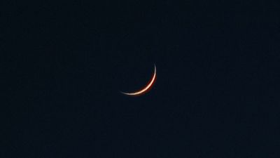 a crescent moon is seen in the dark sky