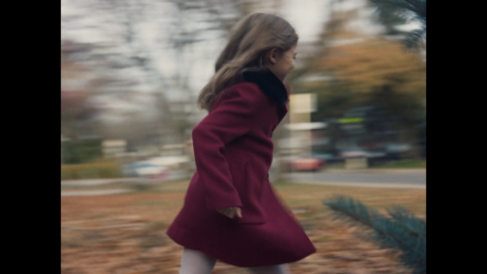 a girl in a red coat is walking down the street