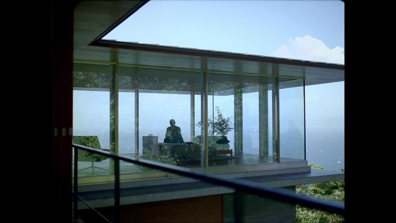 a person sitting on a chair in a room with glass walls