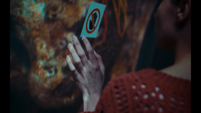 a woman holding a piece of paper in front of a painting