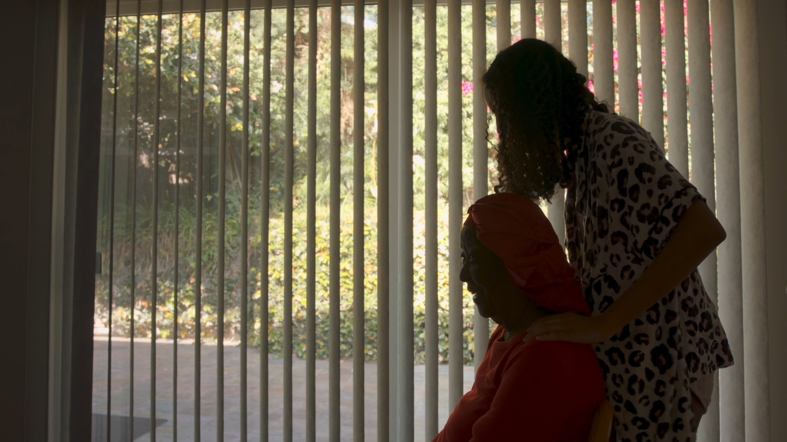 a woman standing next to a man in front of a window