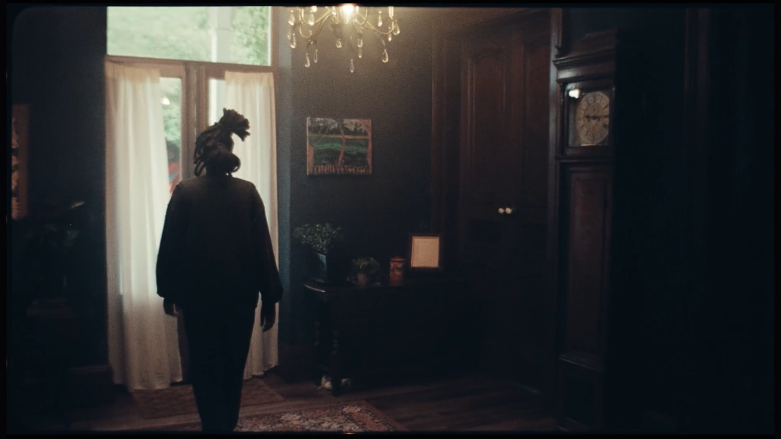 a person standing in a dark room with a chandelier