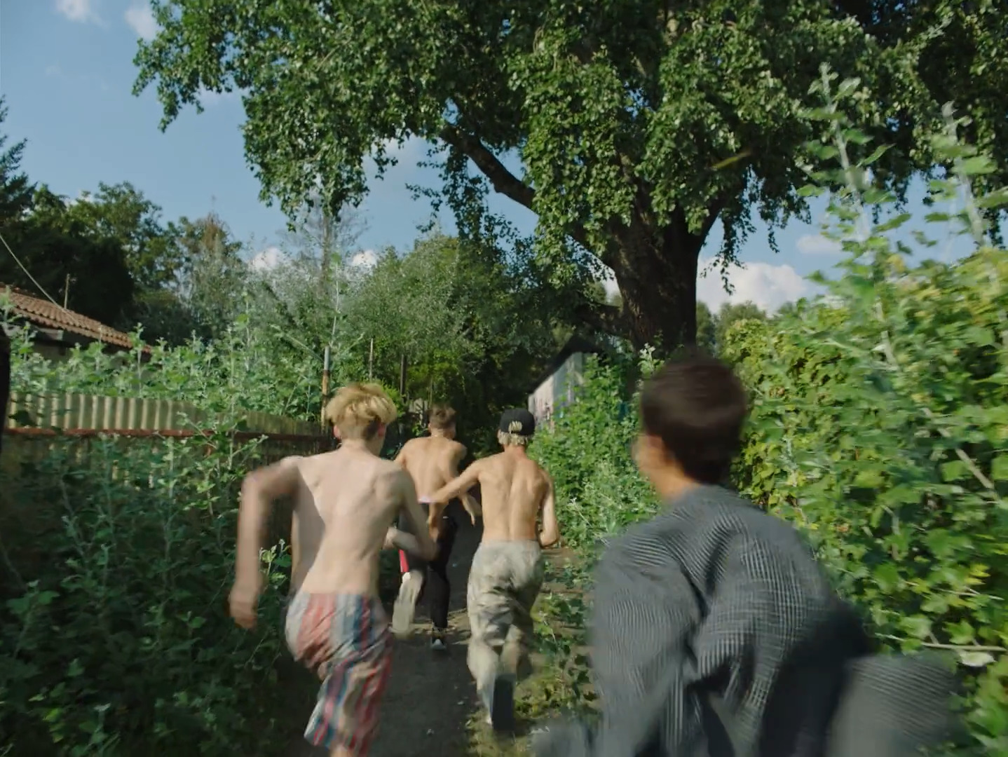 a group of men walking down a street next to a lush green forest