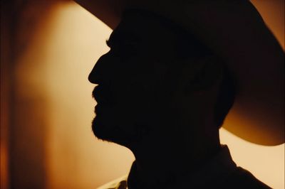 a man wearing a cowboy hat in a dark room