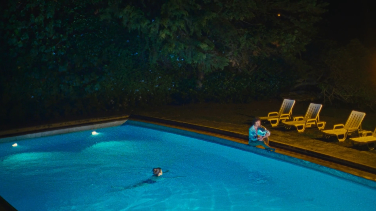 a person sitting in a swimming pool at night