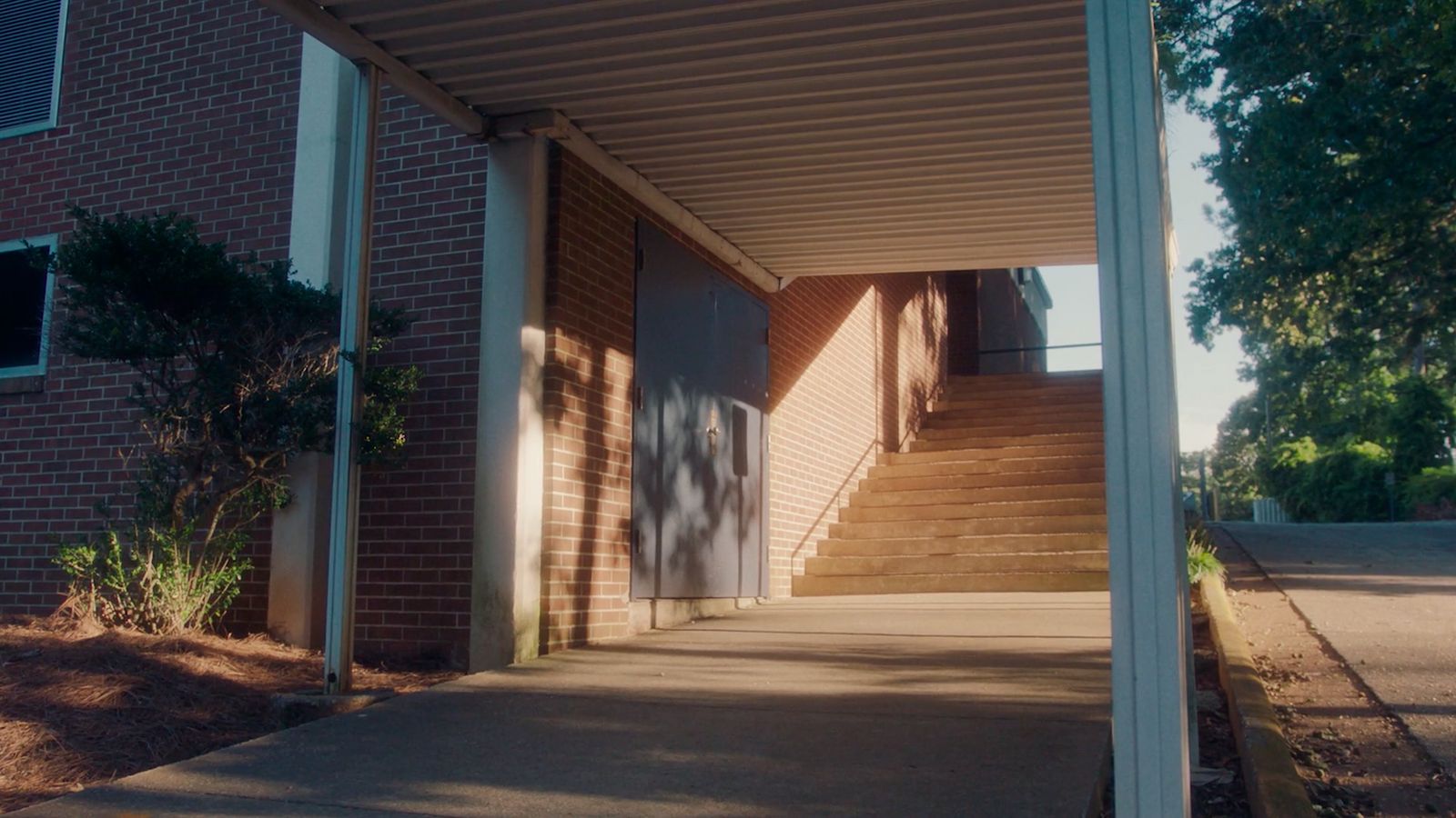 a walkway leading to a brick building with a white door