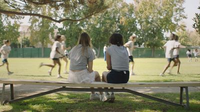 a couple of people sitting on top of a wooden bench