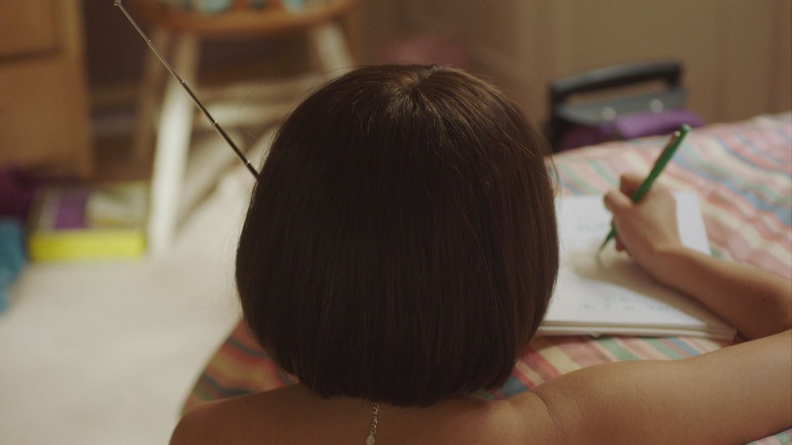 a woman writing in a notebook on a bed